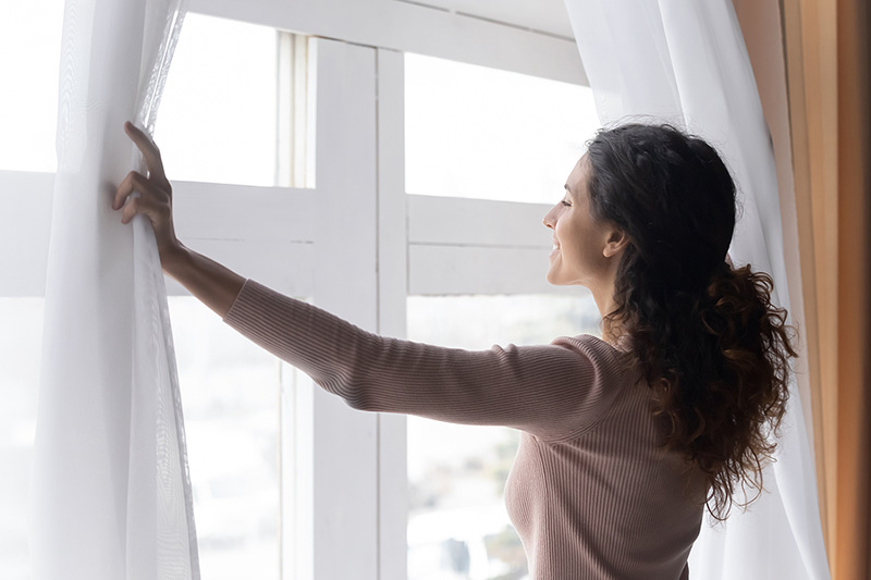 Smiling Woman Opening Curtains In Morning, Enjoying Sun