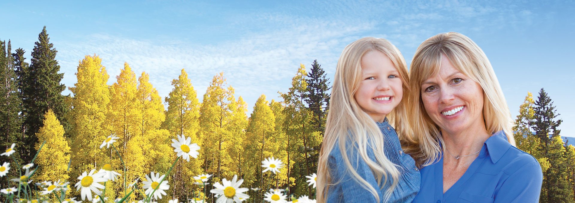 Woman holding young girl in forest setting both are smiling