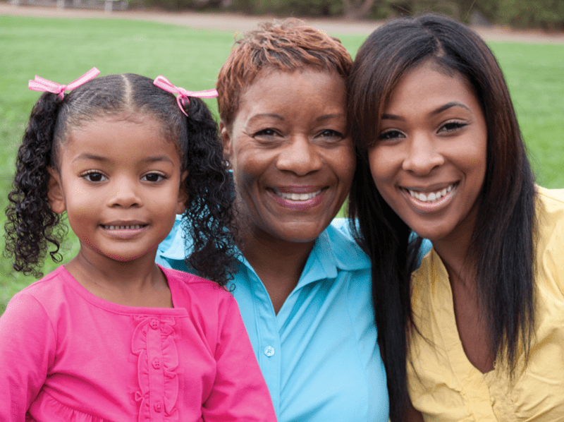 Woman hugging two young girls all are smiling