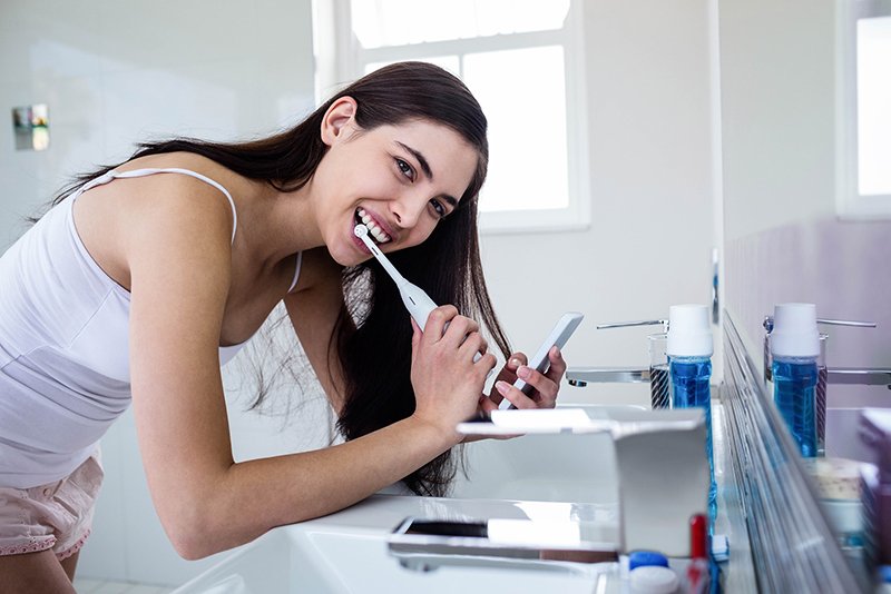 Woman brushing teeth with electric toothbrush